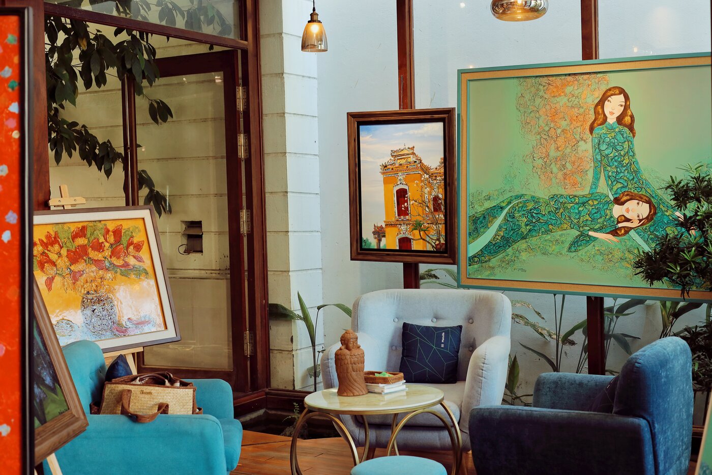 Phòng khách Nhung Art Space với ghế nhung xanh ngọc, tranh thiếu nữ áo dài xanh và ánh sáng từ cửa vòm